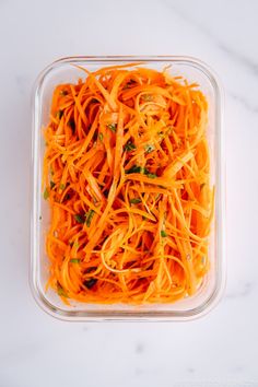 shredded carrots in a plastic container on a white table