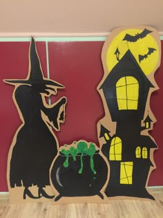 two halloween decorations are on display in front of a red wall