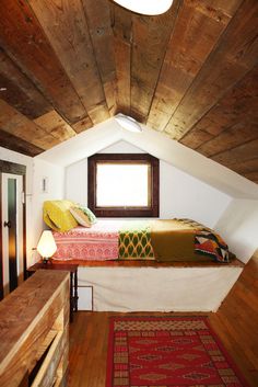 an image of a loft bed in a small room with wooden floors and ceiling beams