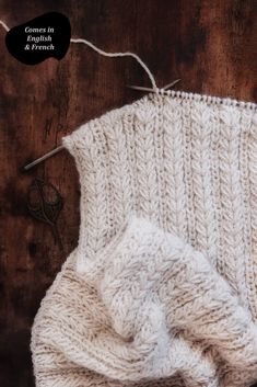 a close up of a knitted object on a wooden surface with scissors and thread