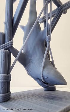 a plastic shark is tied up to a wooden structure with ropes on the top and bottom