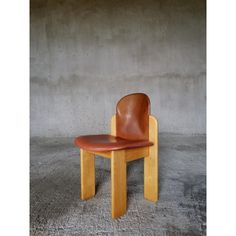 a chair made out of wood and leather on concrete floor with wall in the background