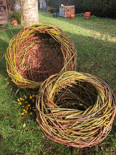 two wicker baskets sitting in the grass next to a tree