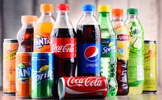 many different types of sodas are lined up on a wooden table with the same color