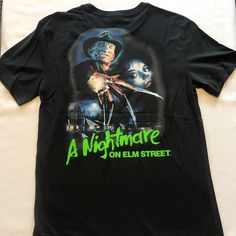 a black t - shirt with an image of a man holding a knife on it