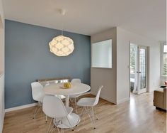 a dining room table with white chairs and a light fixture hanging from the ceiling above it