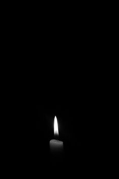 a single candle is lit in the dark