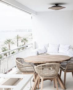 a wooden table sitting on top of a white floor next to two chairs and a couch