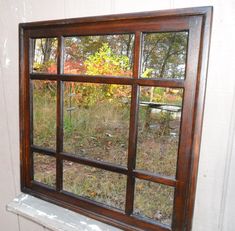 an old window is shown in front of a white wall and some grass with trees outside