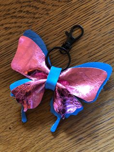 a pink and blue butterfly shaped hair clip on a wooden table with black scissors in it