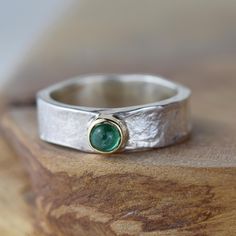 A beautiful silver Storybook band with a cabochon emerald set in solid 9ct yellow gold. The May birthstone ring would make the perfect gift for her. The band is textured with our signature Storybook finish, a leather like design reminiscent of well loved and worn books. The edges move up and down organically as the silver gentle flows around your finger.  Other stones available by special request. Each ring is handmade and you can be sure you're receiving a truly unique piece of jewellery, wheth Cabochon Emerald Ring Gift, Gift Cabochon Emerald Ring, White Gold Emerald Cabochon Ring For Anniversary, Silver Emerald Cabochon Ring, Emerald Jewelry With Bezel Setting In Round Band, Silver Gemstones With Bezel Setting For Anniversary, Emerald Ring With Bezel Setting For Anniversary, White Gold Emerald Ring With Bezel Setting As Gift, Silver Emerald Cabochon Ring In Sterling Silver