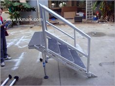 a small metal ramp sitting on top of a cement floor next to a man holding a cell phone