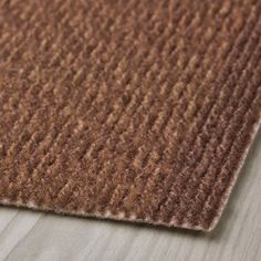 a close up view of a brown rug on the floor with wood grained surface