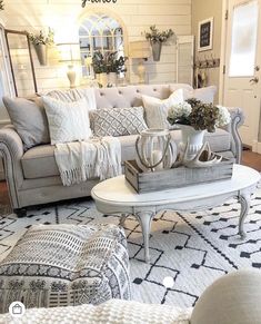 a living room filled with furniture and pillows on top of a white rug in front of a mirror