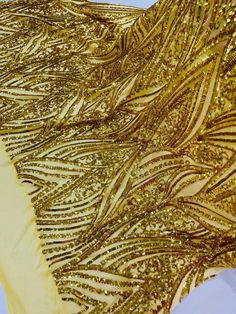 gold sequins and feathers on a white fabric with yellow trim around the edges