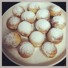 a white plate topped with powdered sugar covered donuts