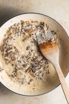 a wooden spoon in a pan filled with mushroom gravy on a counter top