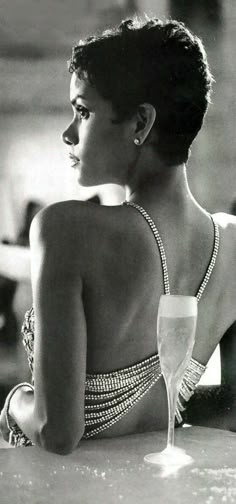 a black and white photo of a woman in a bathing suit sitting at a table