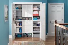 a room with blue walls and white shelves filled with various items, including boxes and baskets