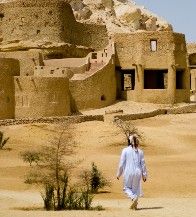 a man walking across a desert covered with sand