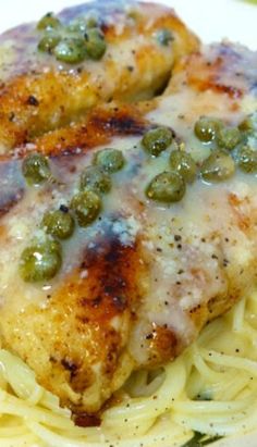 two pieces of chicken with green peas on top of pasta