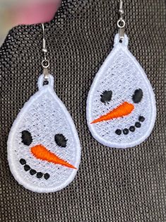 a pair of earrings with a snowman face on it and an orange carrot in the center