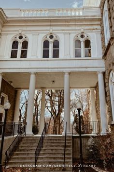 an old building with stairs leading up to the front door and second story windows on each side