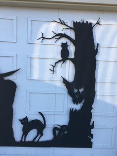 a garage door decorated with halloween decorations and an owl, cat, and tree cutout