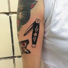 a person with a cat and knife tattoo on their arm