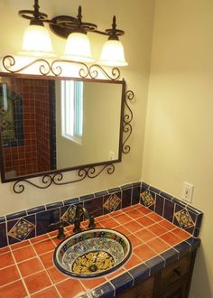 a bathroom sink with a mirror above it and two lights on the wall behind it