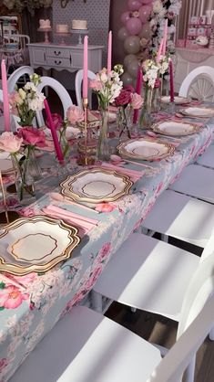 a table set with pink and white flowers, plates and candles for a formal dinner