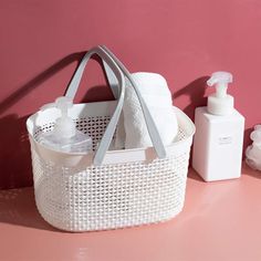 a white basket sitting on top of a pink counter next to bottles and soaps