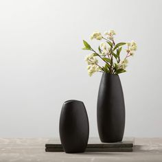 two black vases with white flowers in them