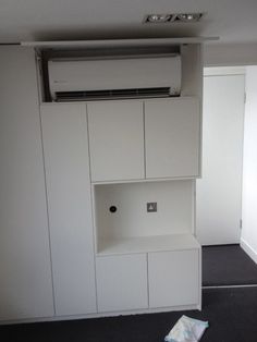 an air conditioner sitting on top of a white cabinet in a room with black carpet