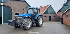 a blue tractor parked in front of a brick building