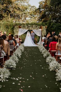 a bride and groom standing at the end of a wedding ceremony aisle with white flowers