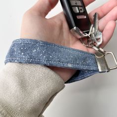 a person holding a cell phone in their left hand with a belt around it's wrist