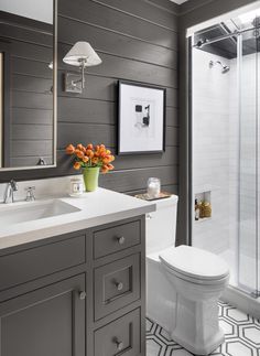 a white toilet sitting under a bathroom mirror next to a sink and a shower stall