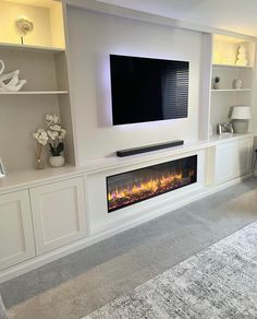 a living room with a large television mounted on the wall and a fire place in front of it