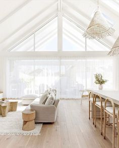 a living room filled with white furniture and wooden flooring next to a dining table