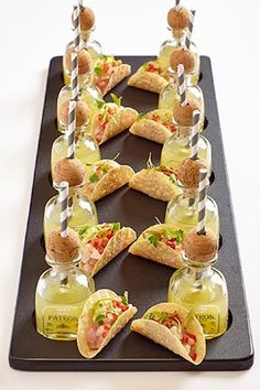 a tray that has some food in small glass bottles on top of it, with toothpicks sticking out of them