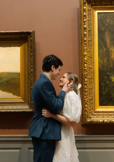 a bride and groom standing next to each other in front of paintings