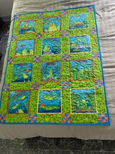 a green and blue quilt on top of a bed