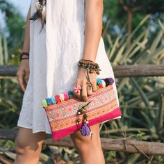 "This beautiful crossbody bag is made with an amazing piece of fabric woven by the HMONG hill tribes of Lanna Country (Northern Thailand). It decorate with multi pom pom. It features a zippered opening area, inside zippered pocket and removable strap. It's a great bag for carrying anything. We buy materials from Hmong market and we design and sew by hand. Some of the bags we modify to improve the product. The Hmong tribes live in the North of Thailand and have origins from the Tibetan area of Ch Bohemian Clutch Pouch For Daily Use, Bohemian Fabric Travel Bag, Bohemian Travel Bags In Fabric, Rectangular Woven Clutch For Festival, Bohemian Summer Clutch Bag, Bohemian Fabric Tote Bag, Traditional Summer Pouch Shoulder Bag, Bohemian Multicolor Embroidery Bags As Gifts, Bohemian Embroidered Clutch Bag