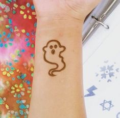 a person with a tattoo on their arm and wrist that has a ghost drawn on it