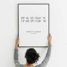 a woman holding up a poster with the coordinates