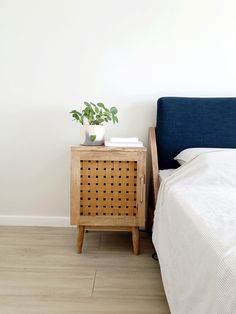 a bed with a blue headboard next to a wooden night stand and white sheets