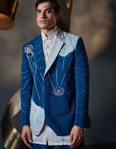 Editor's Note Introducing our blazer set inspired by dali’s infamous painting- spider of the evening 1940. Delicately embroidered with ivory cross and chain stitches, this blazer set weaves a tale of mystery and sophistication. Its unique patchwork contrasting its deep base color echos the enigmatic charm of the night, inviting you to embrace a world of unparalleled elegance. Paired with a white shirt and matching tapered trousers. Fabric: Knit Color: Teal Components: Blazer, shirt and trousers Fairy Types, Painted Blazer, Jatin Malik, Knit Embroidery, Embellished Blazer, Blouse Yoke, Wedding Outfit Men, Dhoti Pants, Stylish Suit