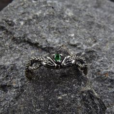 This unique silver engagement ring features a stunning design with twin snakes wrapping around each other, facing each other, and holding a sparkling emerald between their heads. The intricate detailing of the snakes' scales and the vivid green of the emerald make this ring a truly eye-catching piece of jewelry.  Characteristics: Metal - Recycled solid sterling silver  Stone - Cubic Zirconia Finish - Oxidized. View all silver gothic rings: https://www.etsy.com/shop/TinyShinyJewel?ref=seller-platform-mcnav&section_id=42765371 Care instructions: To care for the ring, avoid contact with water and chemicals such as perfumes and lotions. When the ring is not in use, store it in a dry, cool place to prevent tarnishing. Additional information:  ✦ All rings are made to order. An average turnaround Mystical Gemstone Rings For Collectors, Mystical Collectible Gemstone Rings, Silver Fantasy Rings For Anniversary, Sterling Silver Fantasy Style Promise Ring, Fantasy Silver Rings For Anniversary, Fantasy Style Silver Ring For Anniversary, Magical Sterling Silver Crystal Ring For Gift, Mystical White Gold Jewelry Gift, Adjustable Silver Magical Style Rings