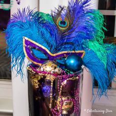 a purple mask with blue feathers and beads on it sitting next to a window sill